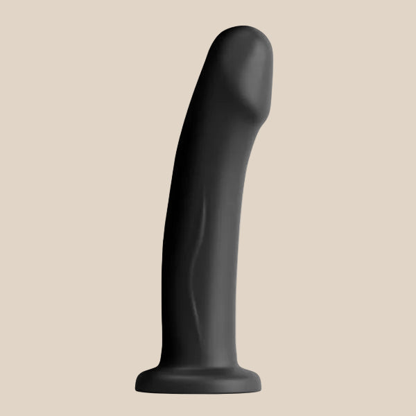 Black silicone curved adult toy with smooth texture and suction base on a beige background