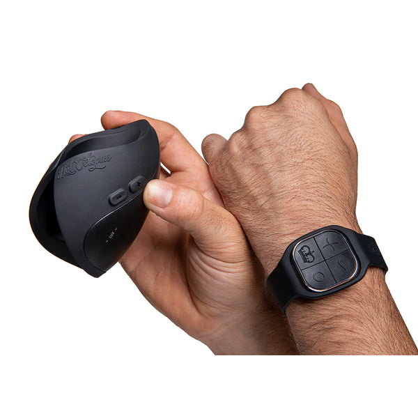 Hand holding a black ergonomic wearable vibrator with remote control wristband