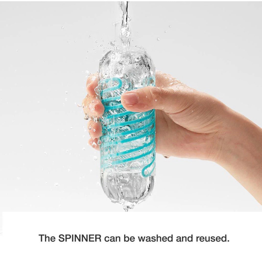 Hand rinsing a transparent reusable adult toy with blue spiral under running water