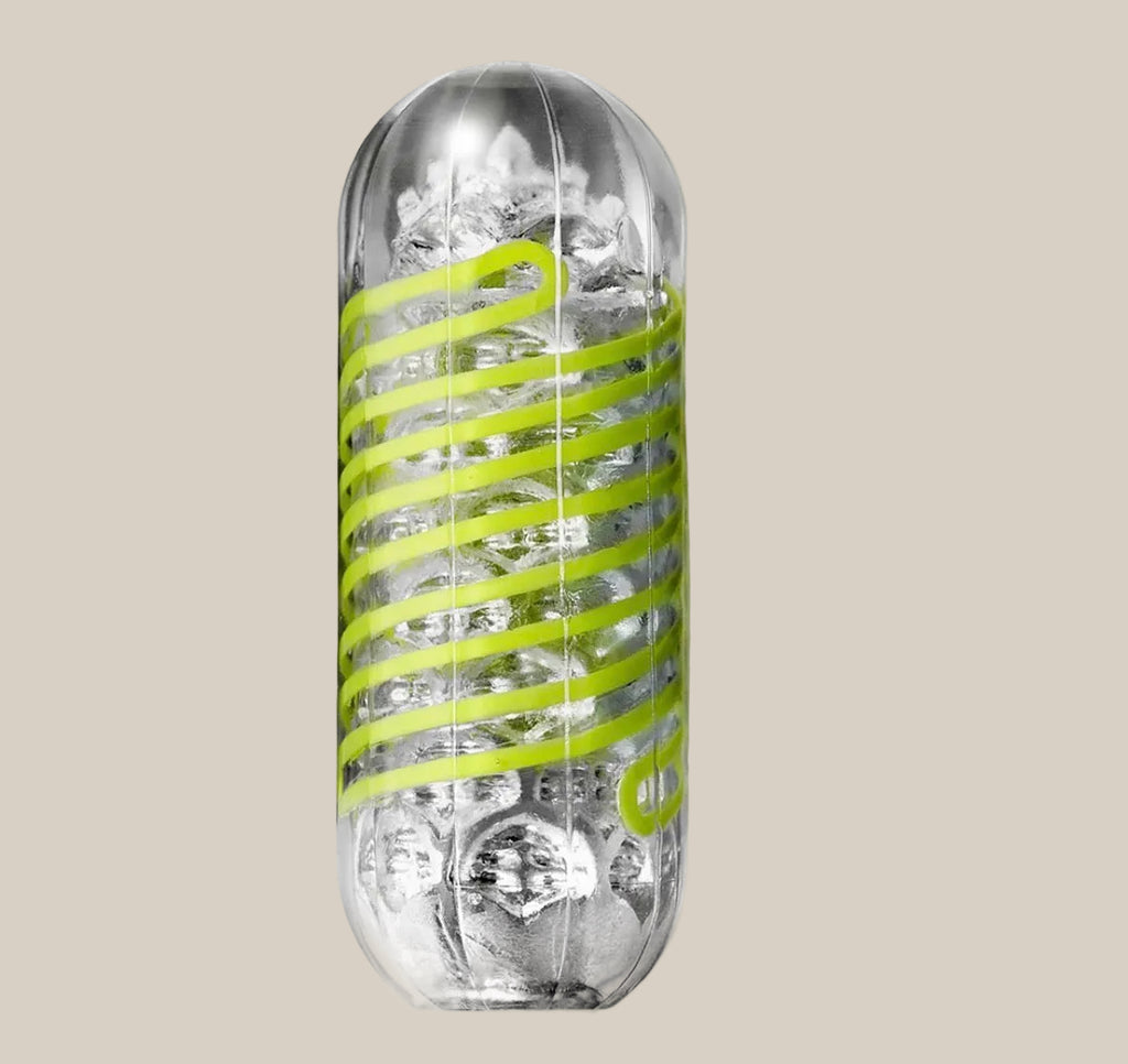 Clear textured adult stroker sleeve with spiral green accent on beige background