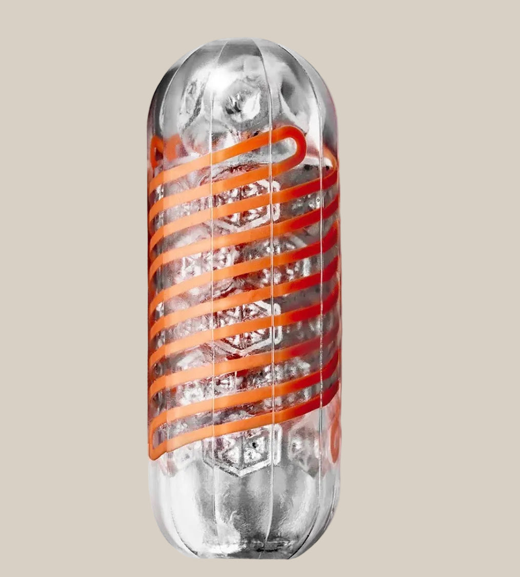 Clear textured adult toy with orange spiral design on neutral background