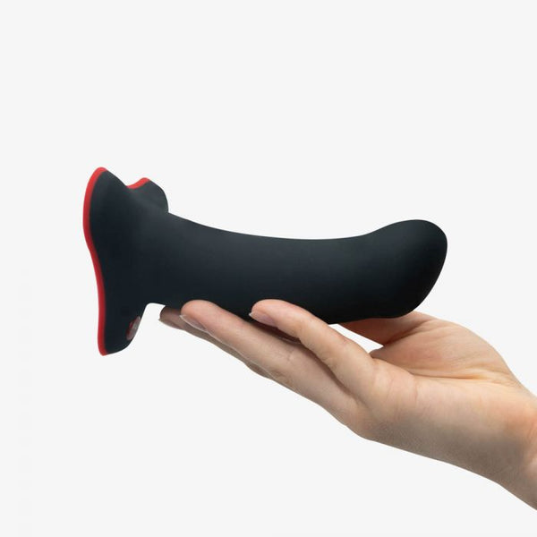 Hand holding a black silicone curved personal massager with red accents on a white background