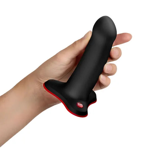 Hand holding a black silicone adult toy with a flared red base, intimacy essential