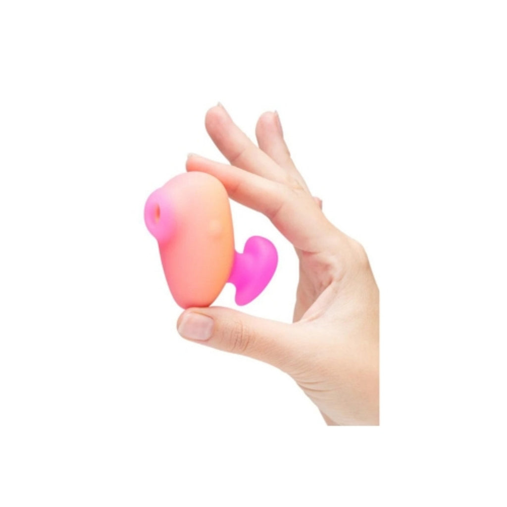 Hand holding pink and orange silicone body-safe personal massager against white background