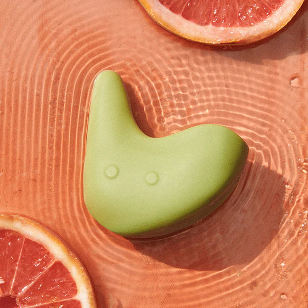 Green waterproof personal massager with grapefruit slices in water