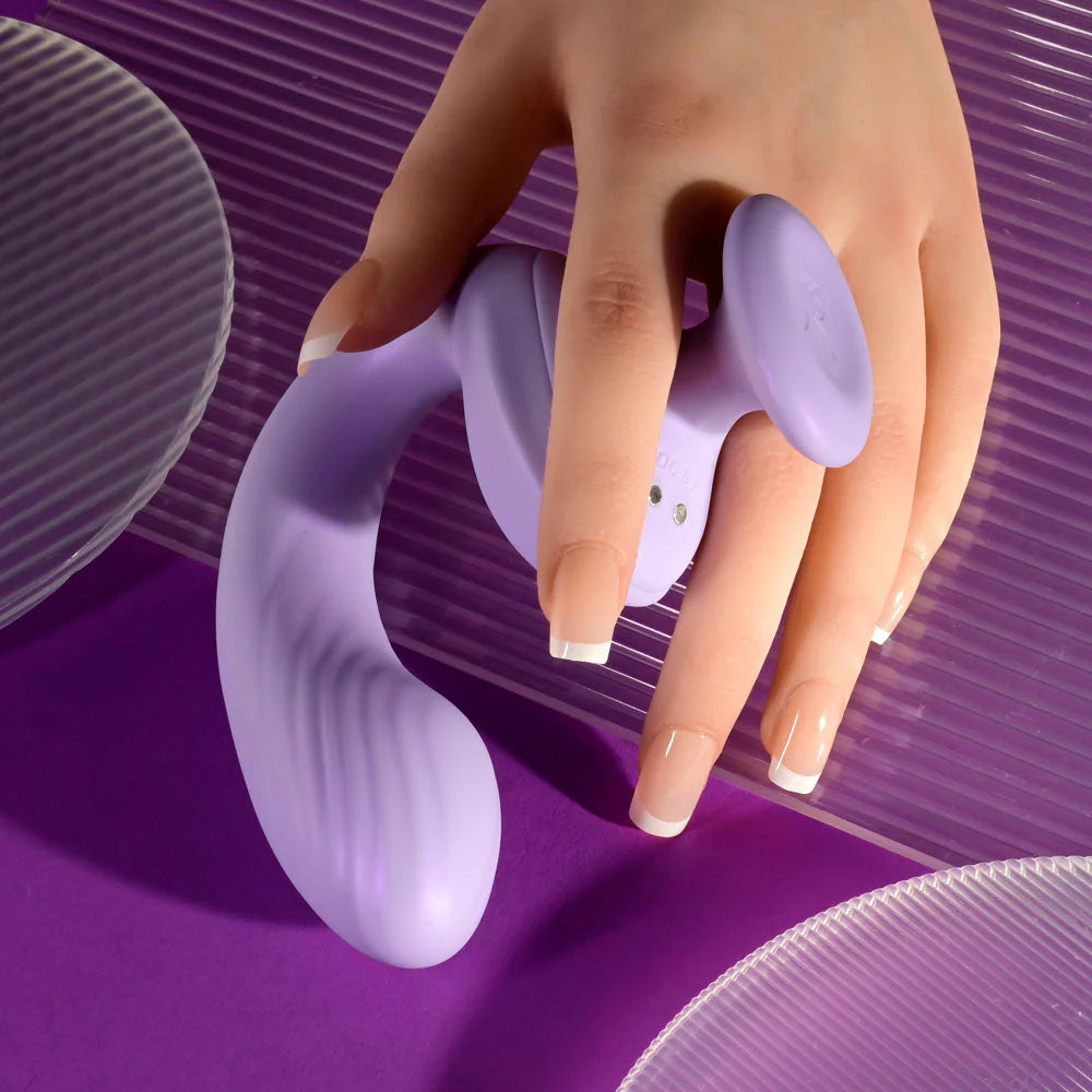 Hand holding a curved purple silicone vibrator on a purple background with textured accents.