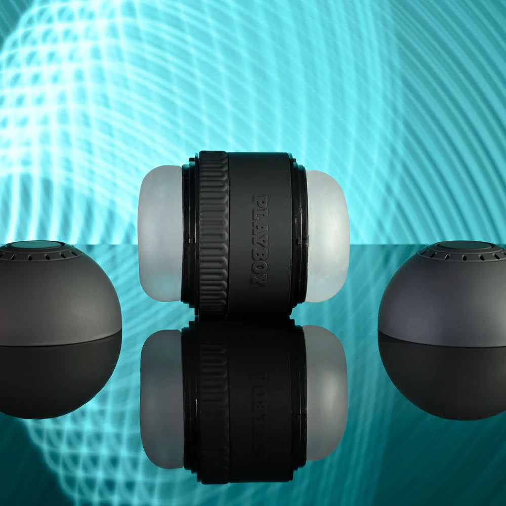 Black and white modern stroker adult toy with detachable end caps on a reflective surface