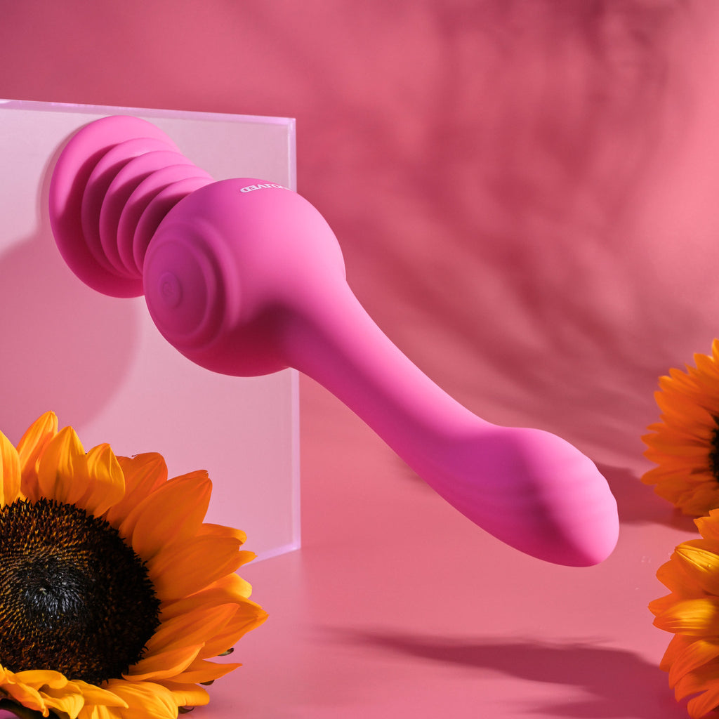 Pink silicone dual-ended adult massager on pink background with sunflowers