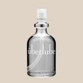 Clear glass bottle of personal lubricant with pump dispenser on neutral background