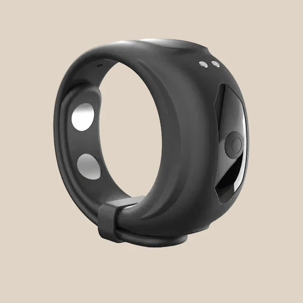Black silicone vibrating ring with buttons and metallic accents on a beige background