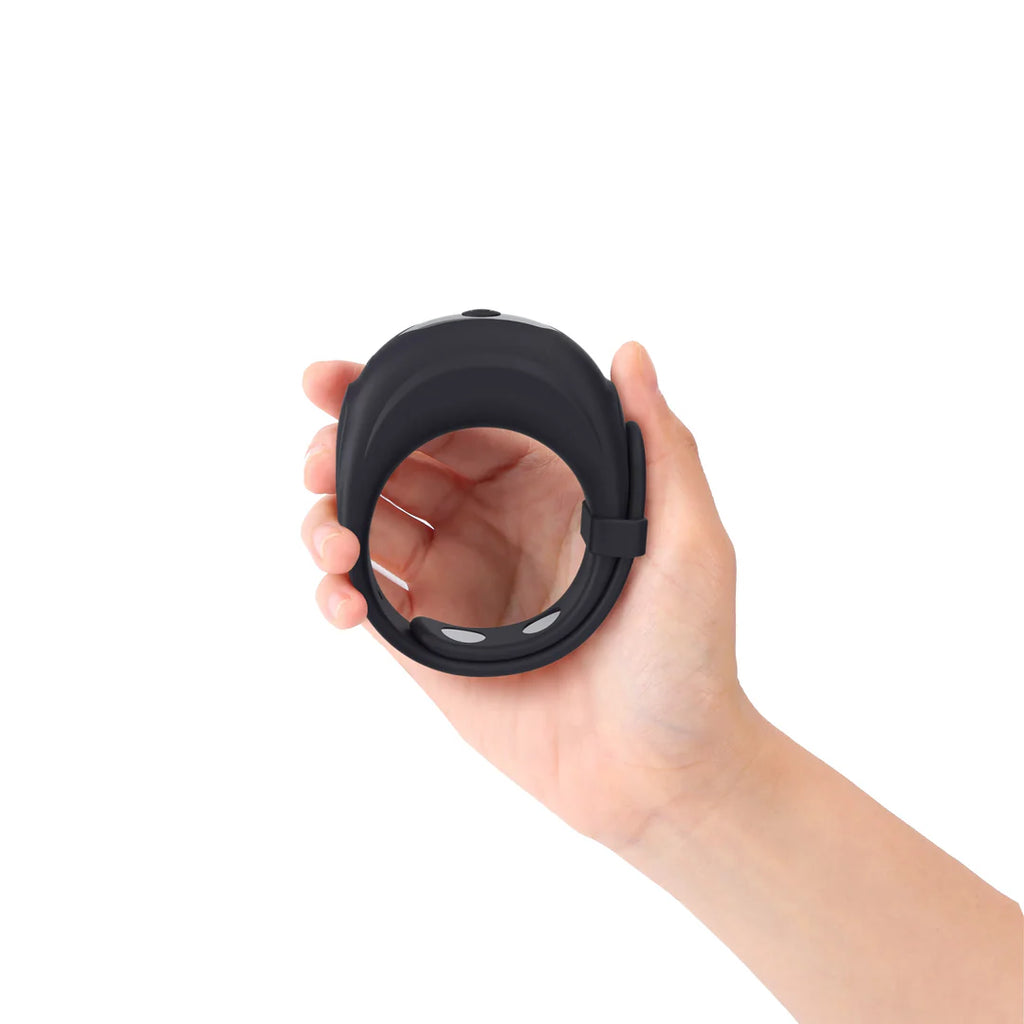 Hand holding a black silicone intimate wearable ring against a white background