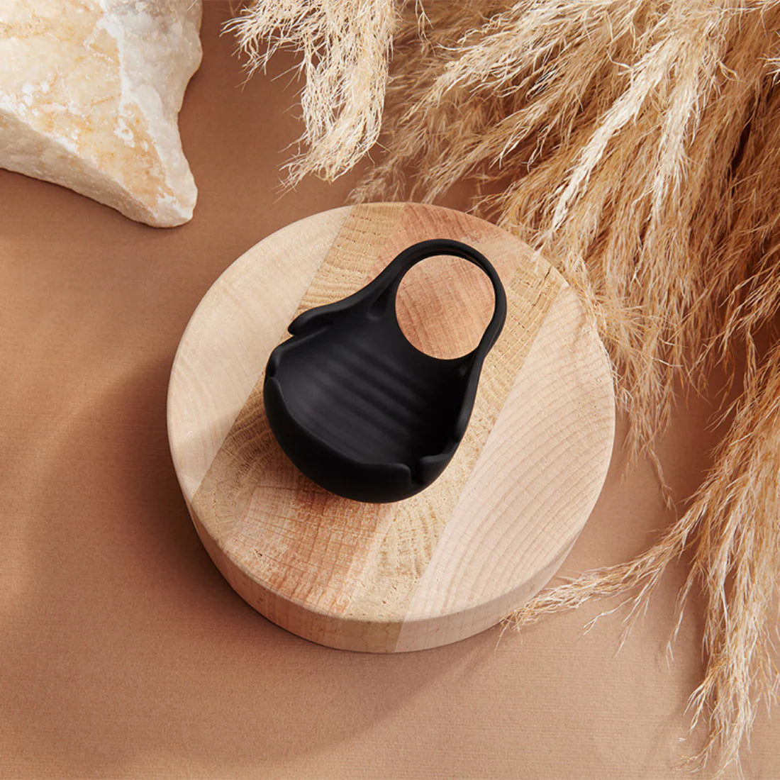 Black silicone vibrating ring on wooden display, intimate adult pleasure product