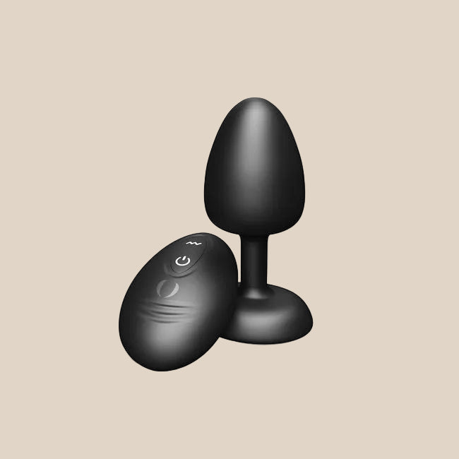 Black silicone vibrating plug with remote control on beige background, adult toy