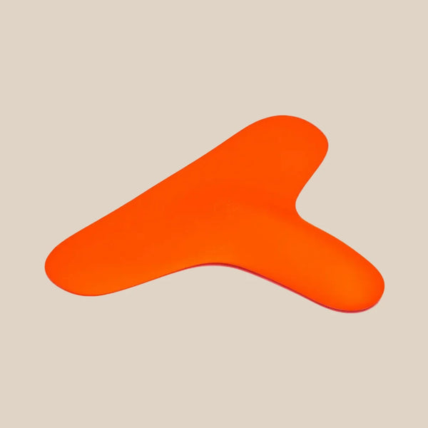 Bright orange silicone adult toy with ergonomic shape on a beige background