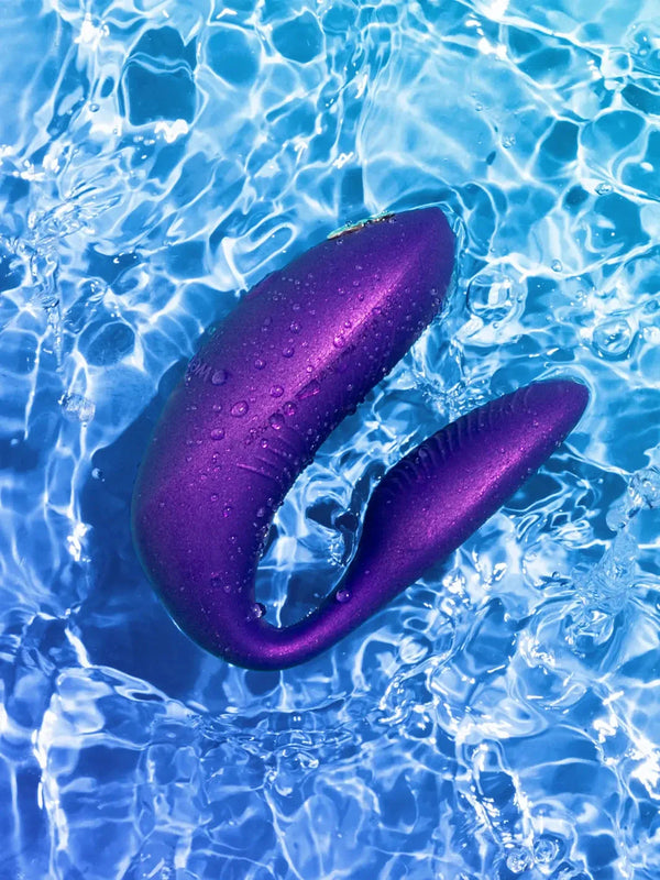 The 100% waterproof We-Vibe Chorus Pro in Cosmic Purple submerged in water, highlighting its submersible design for shower or bath use.