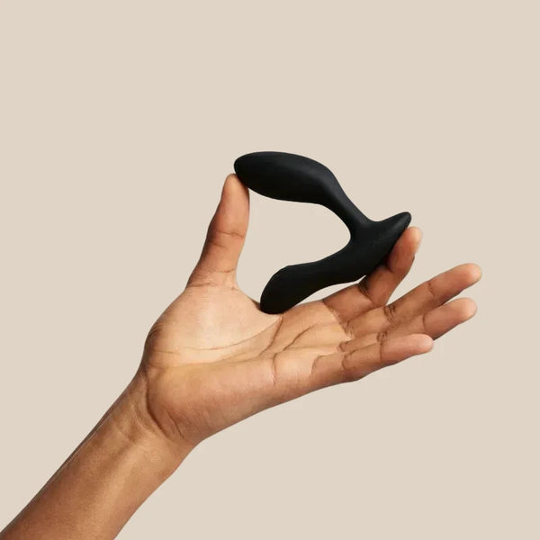 We-Vibe Vector Plus adjustable prostate massager in Charcoal Black held in hand for scale and ergonomic reference at Noirette.