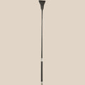 Black riding crop with faux leather tip and handle, sensual adult accessory on beige background
