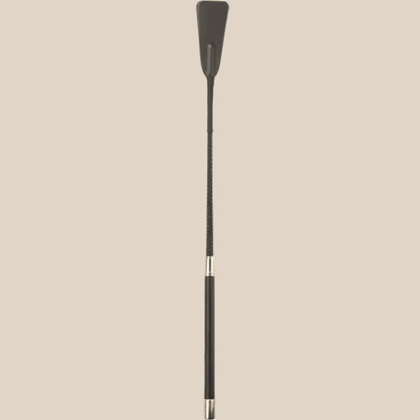 Black faux leather riding crop with silver accents on beige background