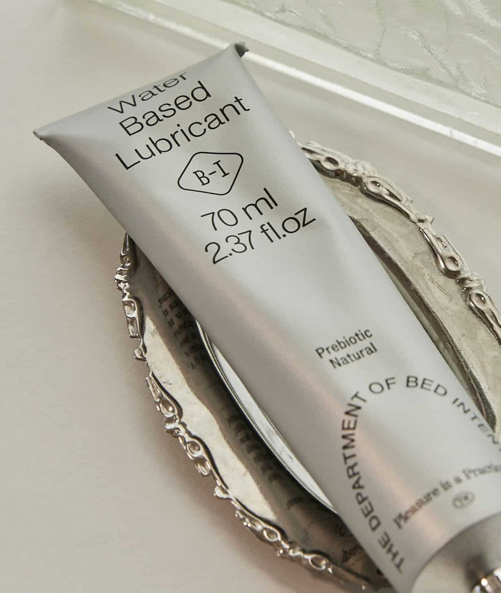 Prebiotic water-based lubricant tube on a decorative tray, 70ml size, minimalist setting