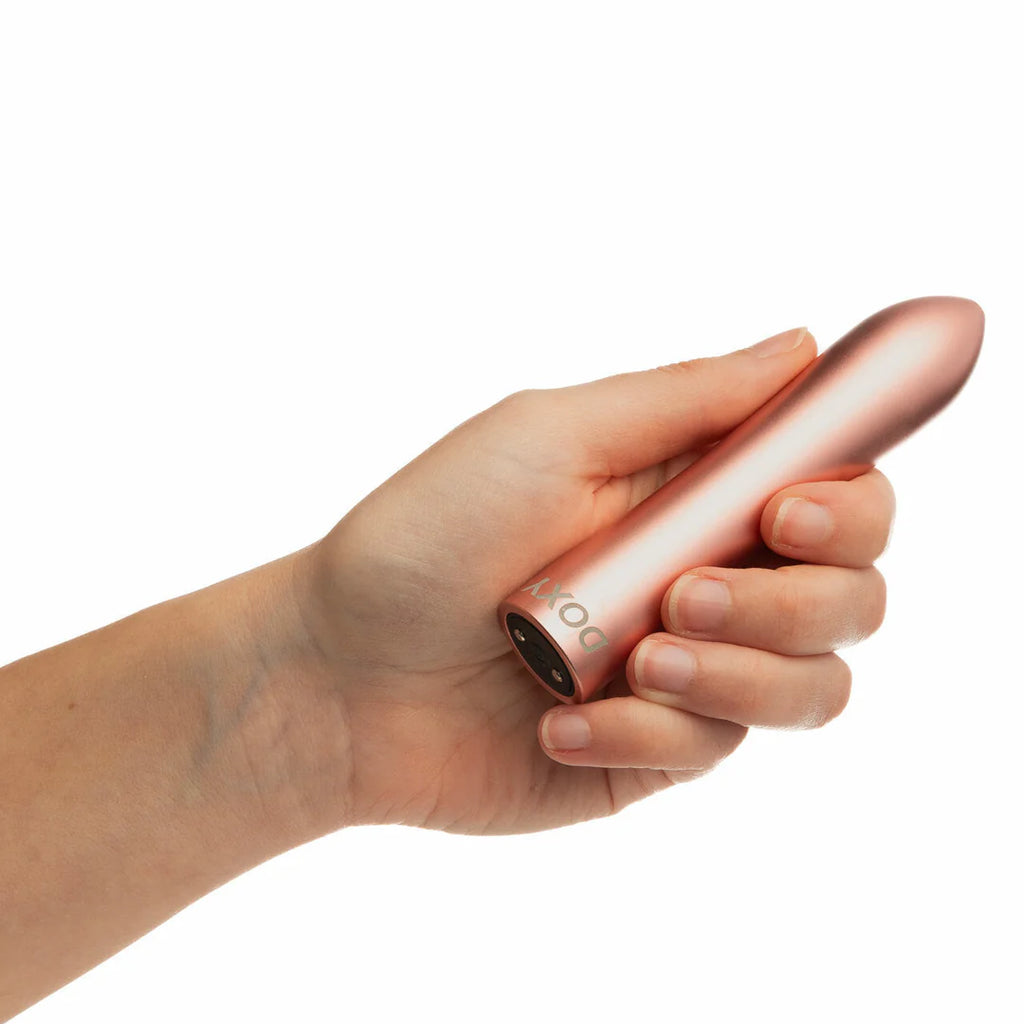Hand holding the elegant rose gold Doxy Bullet pocket vibrator showcasing its high-end metallic finish