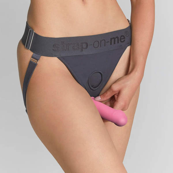 Person wearing adjustable harness briefs with a pink silicone attachment for intimacy.