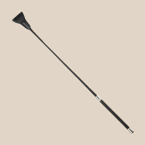 Black leather riding crop with silver accents on beige background