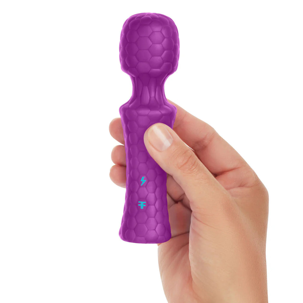 Hand holding a mini purple textured wand massager against a white background