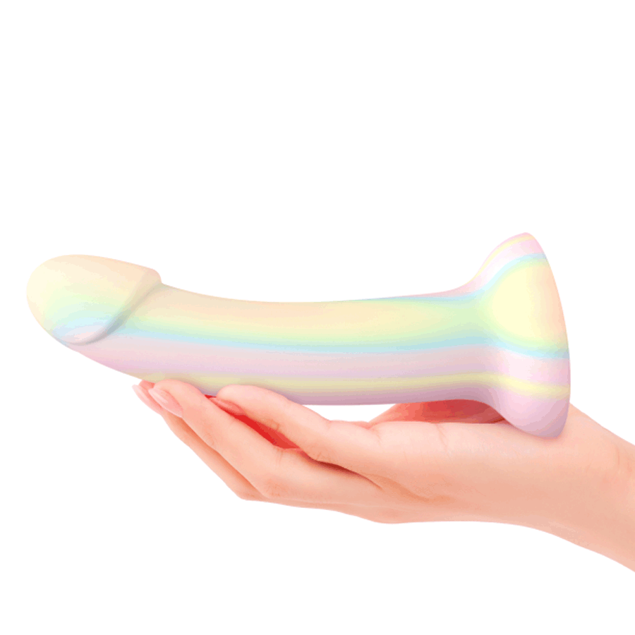 Hand holding a pastel rainbow silicone dildo with realistic shape on white background