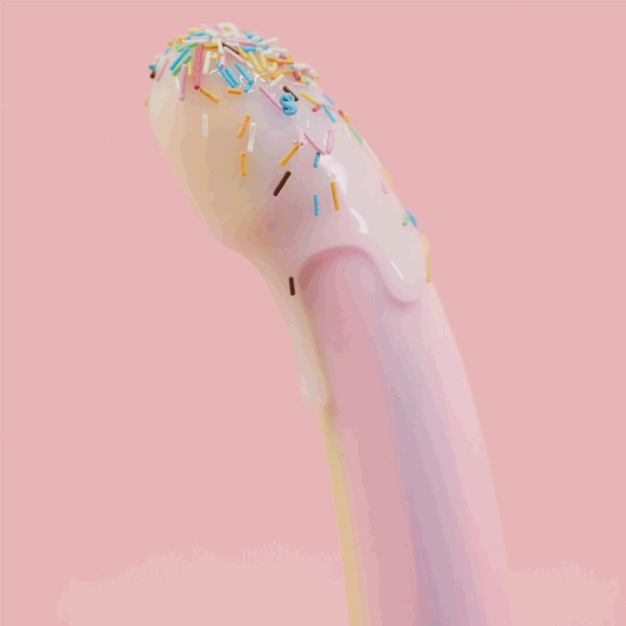 Pink silicone adult toy with icing-like texture and colorful sprinkles on pastel background